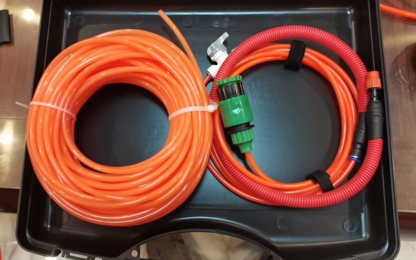 Orange and red hoses coiled in a black toolbox